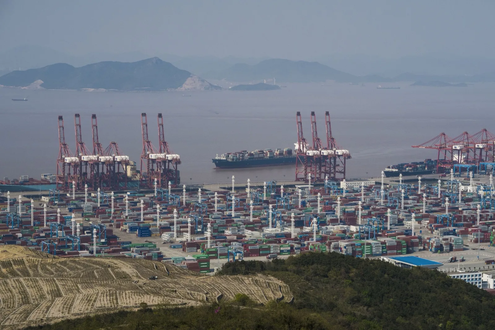 Containerfartyg förtöjt vid Beilunterminalen i Ningbo–Zhoushan, med Zhoushanöarna i bakgrunden